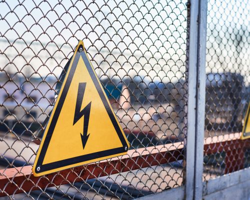 Electrical hazard sign. Lightning on yellow background close up. High voltage electricity on railway station